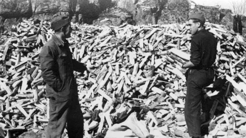 Män som bygger vedförråd under krigstid med stora staplar av ved i bakgrunden.